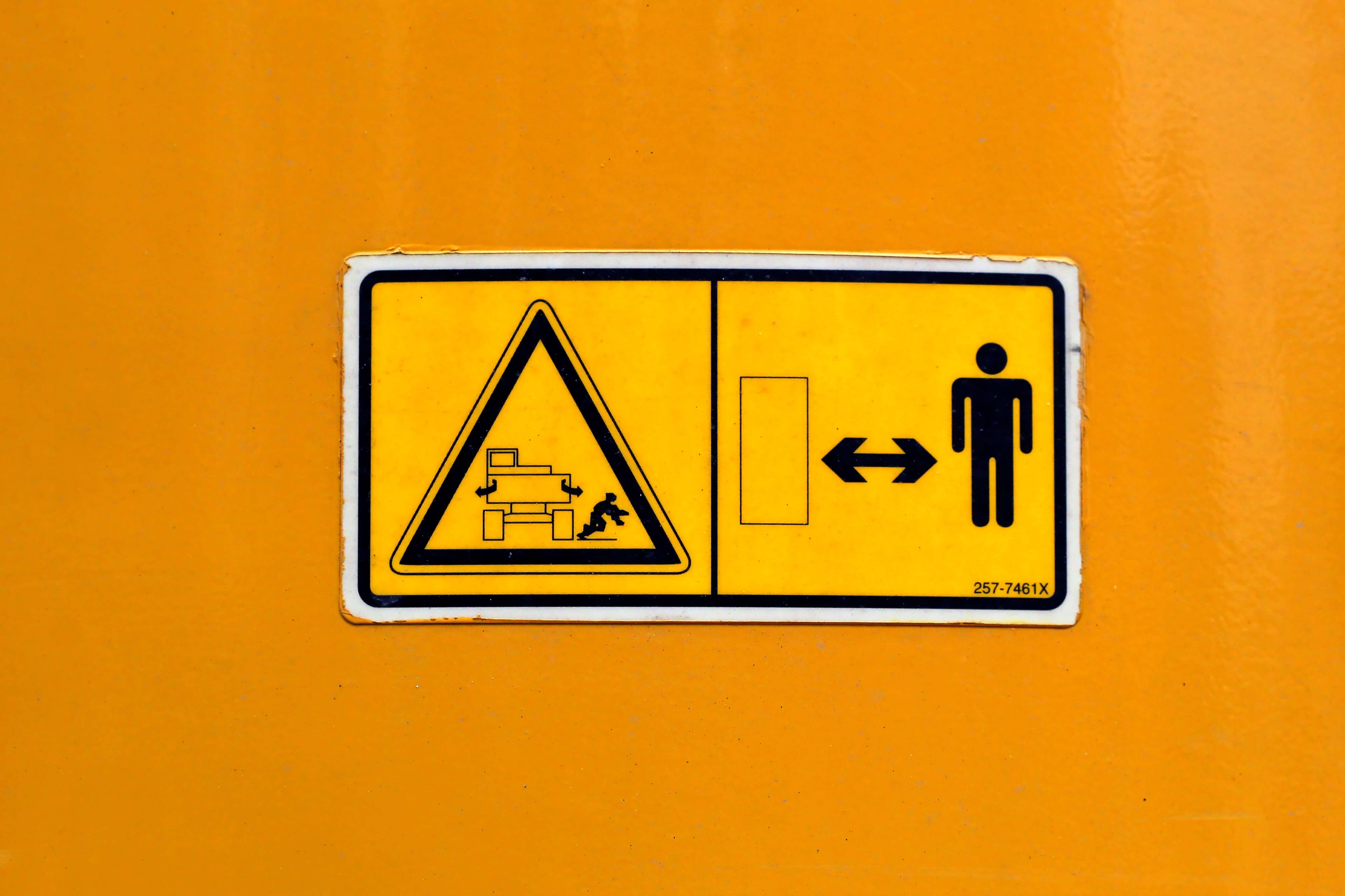 Photo showing yellow warning sign reminding to keep proper distance from machinery.