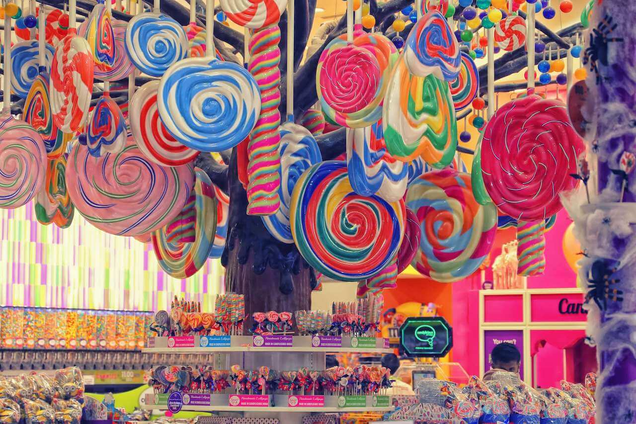 Ecommerce fulfillment for Confectionery. Picture shows the interior of a candy shop, with colourful lollipops hanging from the ceiling and various types of sweets on the shelves. 