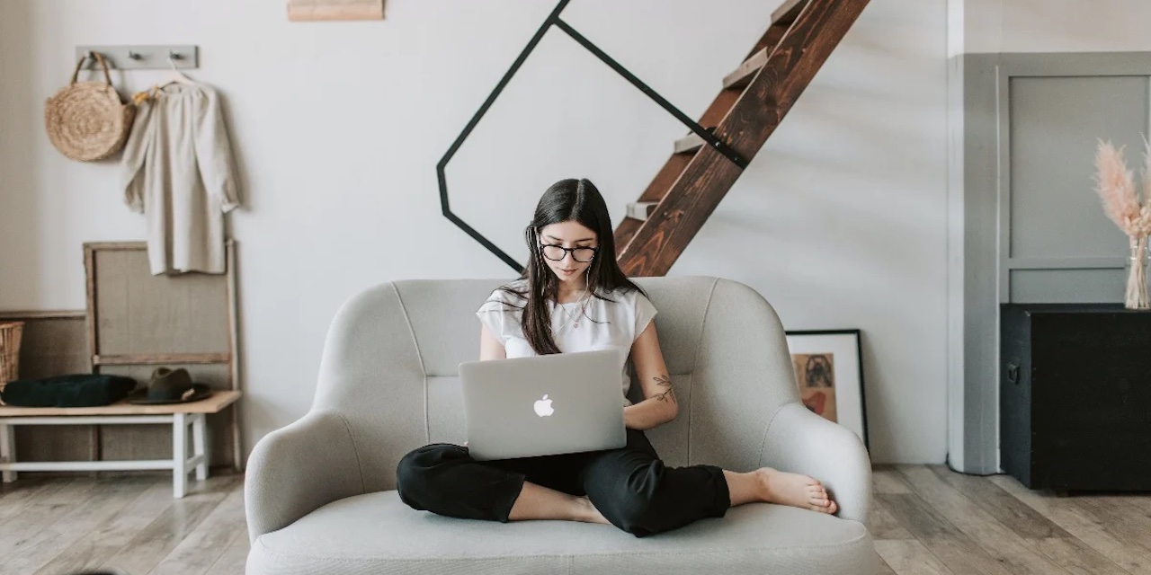 A girl working with a laptop on her lap.